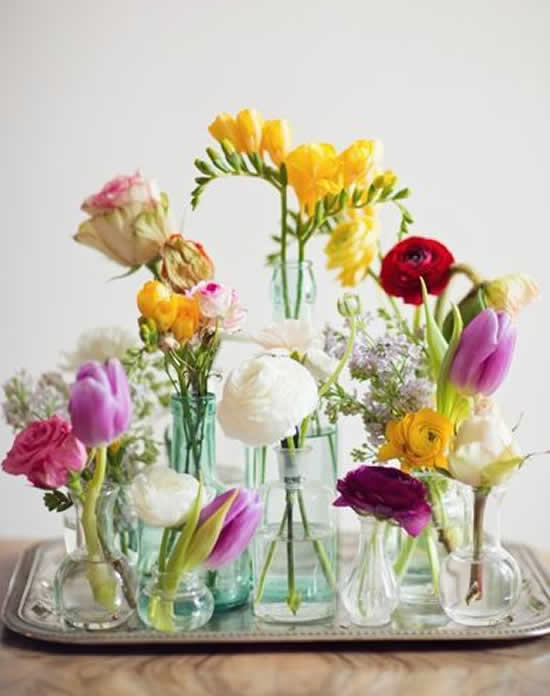 Decoração com arranjos de flores em garrafas de vidro
